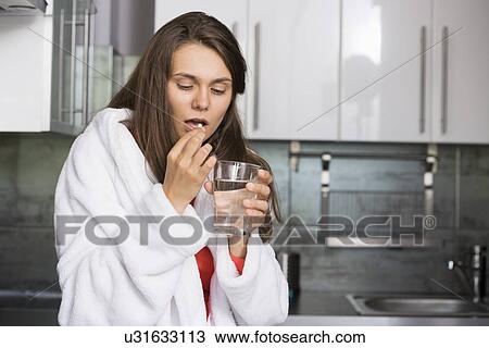 Ill woman taking medicine in kitchen View Large Photo Image Stock Image - Ill woman taking medicine in kitchen. Fotosearch