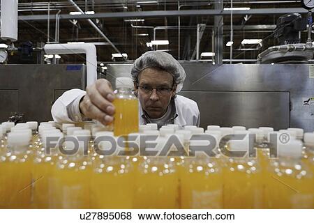 Industrial worker examining bottle in factory View Large Photo Image Stock Photo - Industrial worker examining bottle in factory. Fotosearch