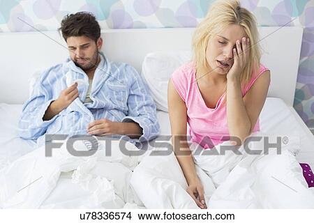 Picture - Irritated sick couple on bed at home. Fotosearch