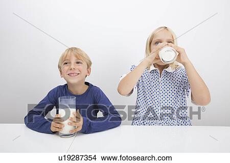 Little children drinking milk at table View Large Photo Image Picture - Little children drinking milk at table. Fotosearch