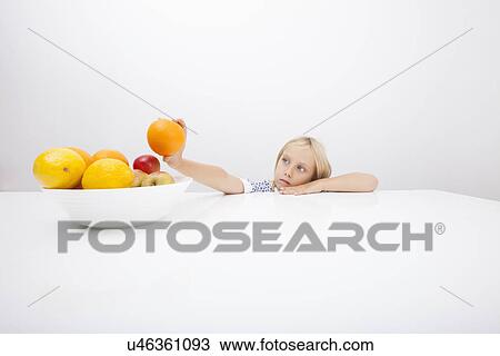 Little girl looking at orange while leaning on table View Large Photo Image Stock Image - Little girl looking at orange while leaning on table. Fotosearch
