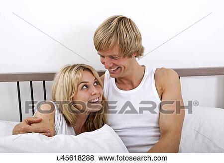 Stock Photo - Loving couple looking at each other in bed. Fotosearch