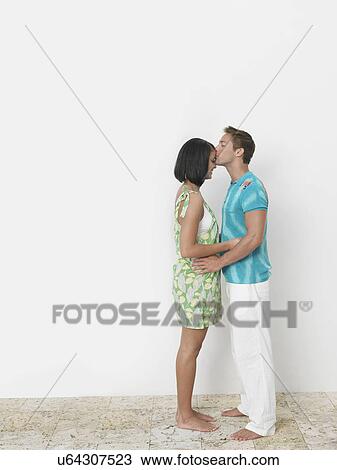 Loving young man kissing woman's forehead against wall View Large Photo Image Stock Image - Loving young man kissing woman's forehead against wall. Fotosearch