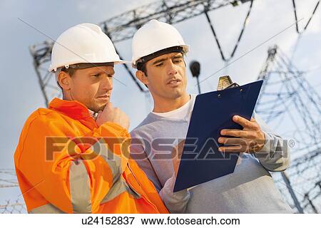 Stock Photo - Low angle view of architects discussing over clipboard. Fotosearch
