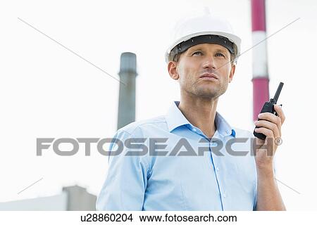 Male architect holding walkie-talkie at site View Large Photo Image Picture - Male architect holding walkie-talkie at site. Fotosearch