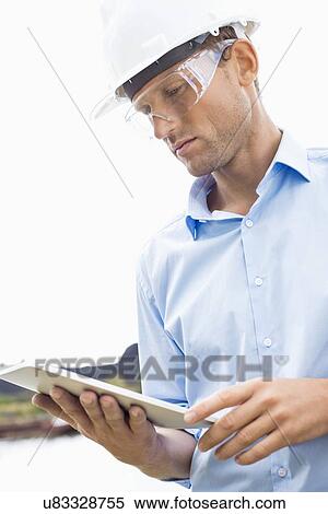 Male architect looking at tablet PC against sky View Large Photo Image Stock Photography - Male architect looking at tablet PC against sky. Fotosearch