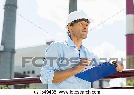 Stock Photo - Male architect with clipboard and pen at site. Fotosearch