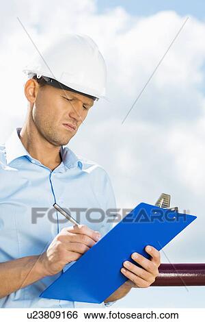 Male architect writing on clipboard against cloudy sky View Large Photo Image Stock Photograph - Male architect writing on clipboard against cloudy sky. Fotosearch