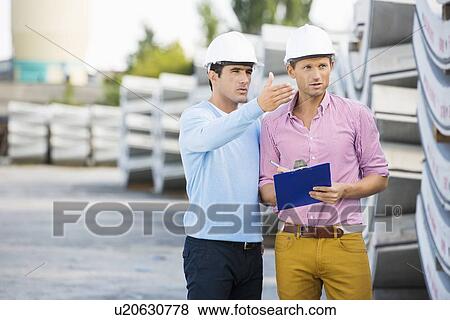 Stock Photo - Male architects inspecting inventory at site. Fotosearch