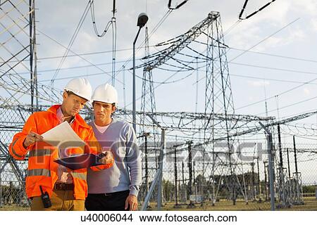 Picture - Male architects reviewing documents together at electric power plant. Fotosearch