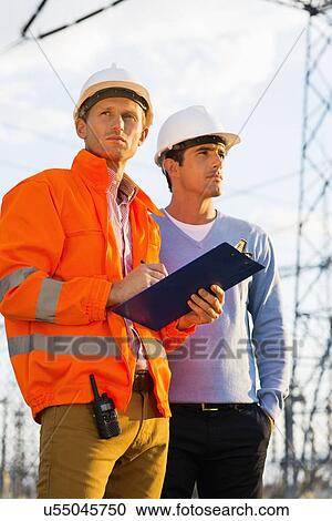 Stock Image - Male architects with clipboard inspecting site together. Fotosearch