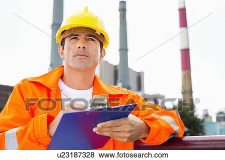 Male construction worker writing on clipboard at industry View Large Photo Image Stock Photo - Male construction worker writing on clipboard at industry. Fotosearch