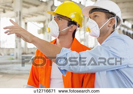 Male construction workers having a discussion at site View Large Photo Image Stock Image - Male construction workers having a discussion at site. Fotosearch