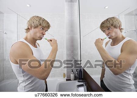 Stock Photograph - Man brushing teeth in bathroom. Fotosearch