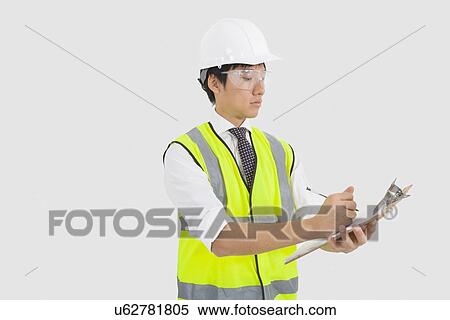 Man in reflector vest and hard hat writing on clipboard in office View Large Photo Image Stock Photography - Man in reflector vest and hard hat writing on clipboard in office. Fotosearch
