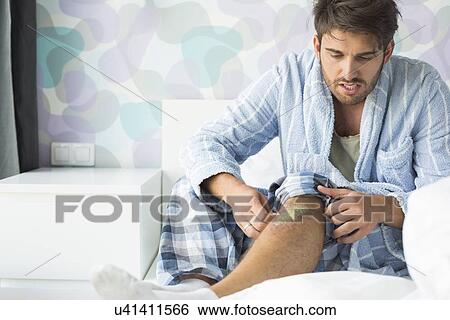 Man looking at wound on bed at home View Large Photo Image Stock Photograph - Man looking at wound on bed at home. Fotosearch