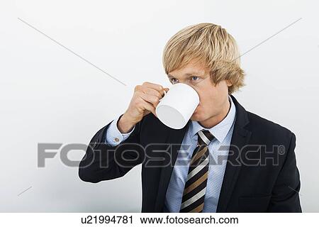Stock Image - Mid adult businessman drinking coffee over white background. Fotosearch