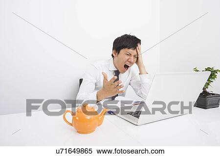 Mid adult businessman screaming with laptop on desk in office View Large Photo Image Stock Photography - Mid adult businessman screaming with laptop on desk in office. Fotosearch