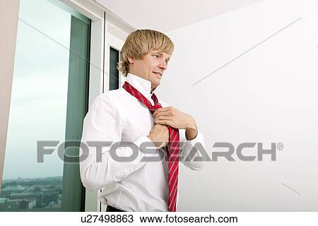 Mid adult businessman tying tie at home View Large Photo Image Stock Image - Mid adult businessman tying tie at home. Fotosearch