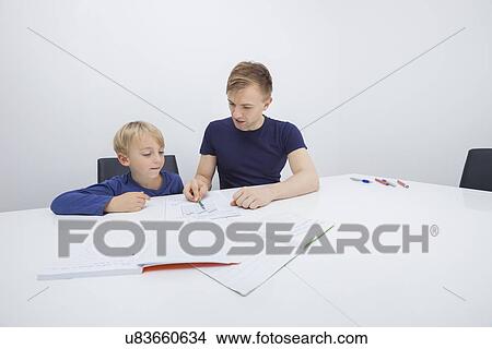 Mid adult father assisting boy in studies View Large Photo Image Picture - Mid adult father assisting boy in studies. Fotosearch
