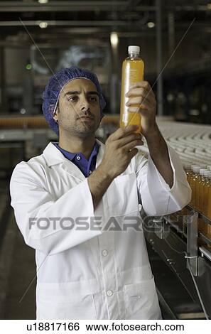 Mid adult industrial worker examining bottle in factory View Large Photo Image Stock Photograph - Mid adult industrial worker examining bottle in factory. Fotosearch