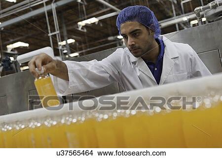 Mid adult industrial worker looking at bottle in factory View Large Photo Image Picture - Mid adult industrial worker looking at bottle in factory. Fotosearch