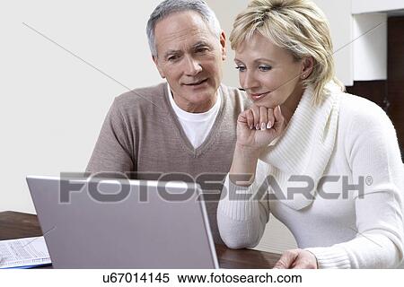 Middle-aged couple counting bills using laptop in kitchen View Large Photo Image Stock Photography - Middle-aged couple counting bills using laptop in kitchen. Fotosearch