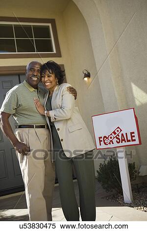 Stock Photography - Middle-aged couple in front of new home. Fotosearch