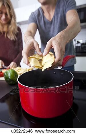 Stock Photograph - Midsection of man cooking pasta in kitchen. Fotosearch