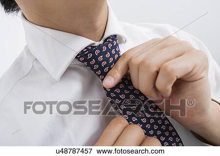 Stock Photo - Midsection of mid adult businessman adjusting tie. Fotosearch
