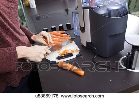 Midsection of woman chopping carrots on cutting board in kitchen View Large Photo Image Stock Photo - Midsection of woman chopping carrots on cutting board in kitchen. Fotosearch