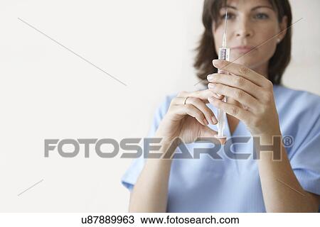 Stock Image - Nurse Preparing syringe For Injection focus on syringe. Fotosearch