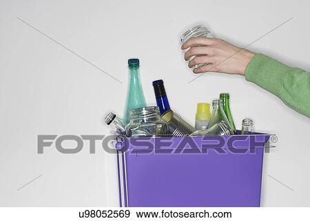 Stock Photo - Person putting jar into recycling container filled with empty glass vessels. Fotosearch