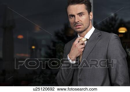 Portrait of angry businessman adjusting necktie in office View Large Photo Image Stock Image - Portrait of angry businessman adjusting necktie in office. Fotosearch