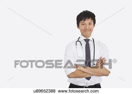 Portrait of Asian male doctor with arms crossed over white background View Large Photo Image Stock Photo - Portrait of Asian male doctor with arms crossed over white background. Fotosearch
