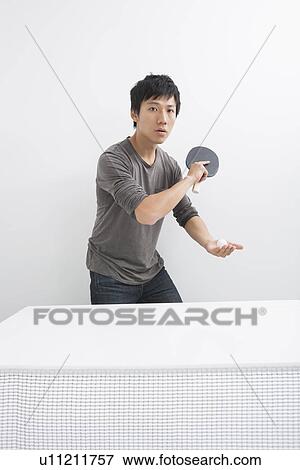 Stock Photo - Portrait of Asian mid adult man playing table tennis. Fotosearch