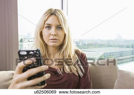 Portrait of beautiful young woman with mobile phone at home View Large Photo Image Stock Photo - Portrait of beautiful young woman with mobile phone at home. Fotosearch