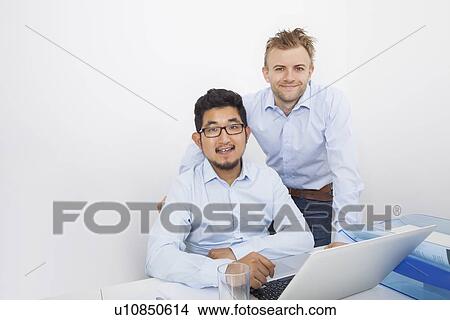 Portrait of businessmen with laptop at desk in office View Large Photo Image Picture - Portrait of businessmen with laptop at desk in office. Fotosearch