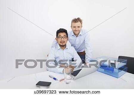 Portrait of businesspeople with laptop at desk in office View Large Photo Image Stock Image - Portrait of businesspeople with laptop at desk in office. Fotosearch