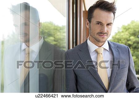 Portrait of confident businessman leaning on glass door View Large Photo Image Stock Image - Portrait of confident businessman leaning on glass door. Fotosearch
