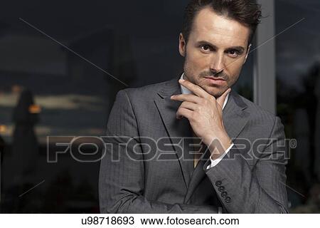 Portrait of confident businessman with hand on chin in office View Large Photo Image Stock Image - Portrait of confident businessman with hand on chin in office. Fotosearch