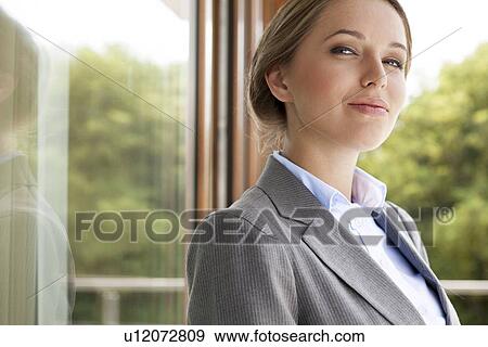 Stock Photo - Portrait of confident businesswoman by glass door. Fotosearch