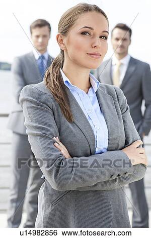 Portrait of confident businesswoman standing arms crossed with coworkers in background on terrace View Large Photo Image Stock Photograph - Portrait of confident businesswoman standing arms crossed with coworkers in background on terrace. Fotosearch