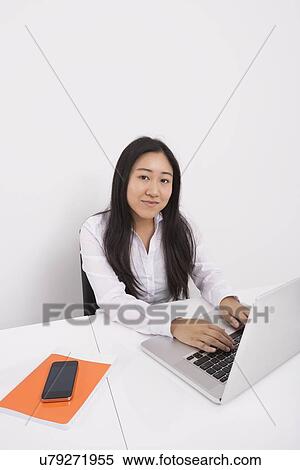 Portrait of confident businesswoman working on laptop in office View Large Photo Image Stock Photography - Portrait of confident businesswoman working on laptop in office. Fotosearch