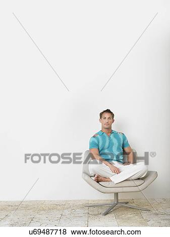 Portrait of confident young man sitting on chair View Large Photo Image Stock Photo - Portrait of confident young man sitting on chair. Fotosearch