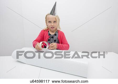 Portrait of cute girl wrapping birthday gift at table in house View Large Photo Image Stock Photo - Portrait of cute girl wrapping birthday gift at table in house. Fotosearch
