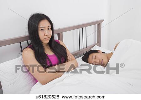 Portrait of displeased woman with man sleeping in bed View Large Photo Image Stock Photo - Portrait of displeased woman with man sleeping in bed. Fotosearch