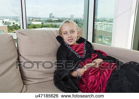 Stock Photograph - Portrait of girl in vampire costume relaxing on sofa at home. Fotosearch