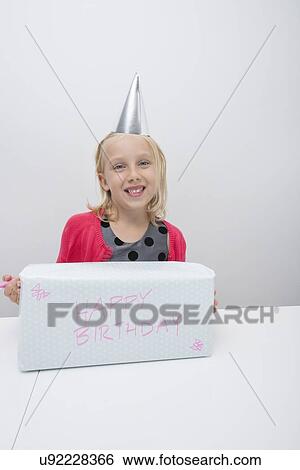 Portrait of girl with birthday gift at table in house View Large Photo Image Stock Photograph - Portrait of girl with birthday gift at table in house. Fotosearch