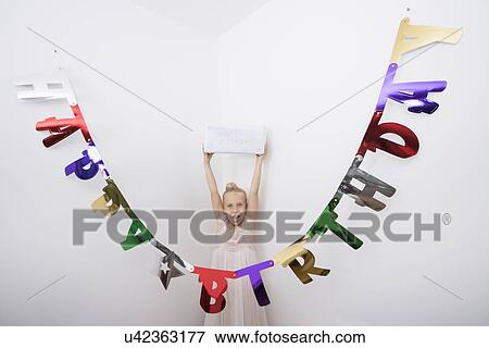 Stock Photo - Portrait of girl with mouth open holding birthday gift over head. Fotosearch